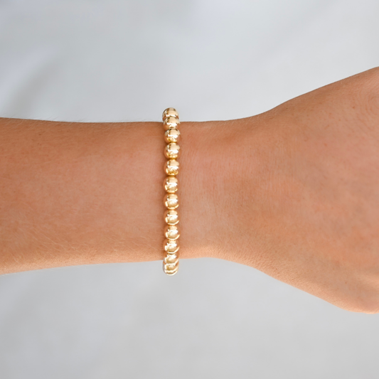 Gold filled LustraFlex™ bracelet bracelet on a wrist against a light gray background