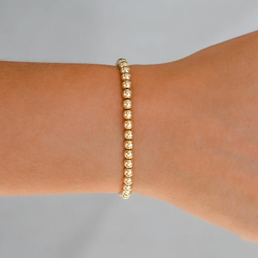 Gold LustraFlex™ bracelet on a wrist against a gray background. Gold Club by Shannon Hudson