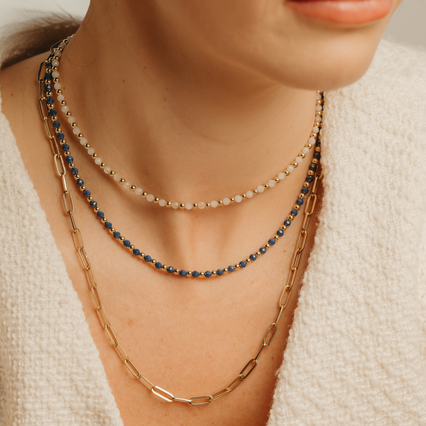 Layered necklaces from Gold Club by Shannon Hudson featuring the Kyanite Balanced Necklace with blue gemstones, the White Moonstone Balanced Necklace, and a 14k gold-filled Paperclip Necklace