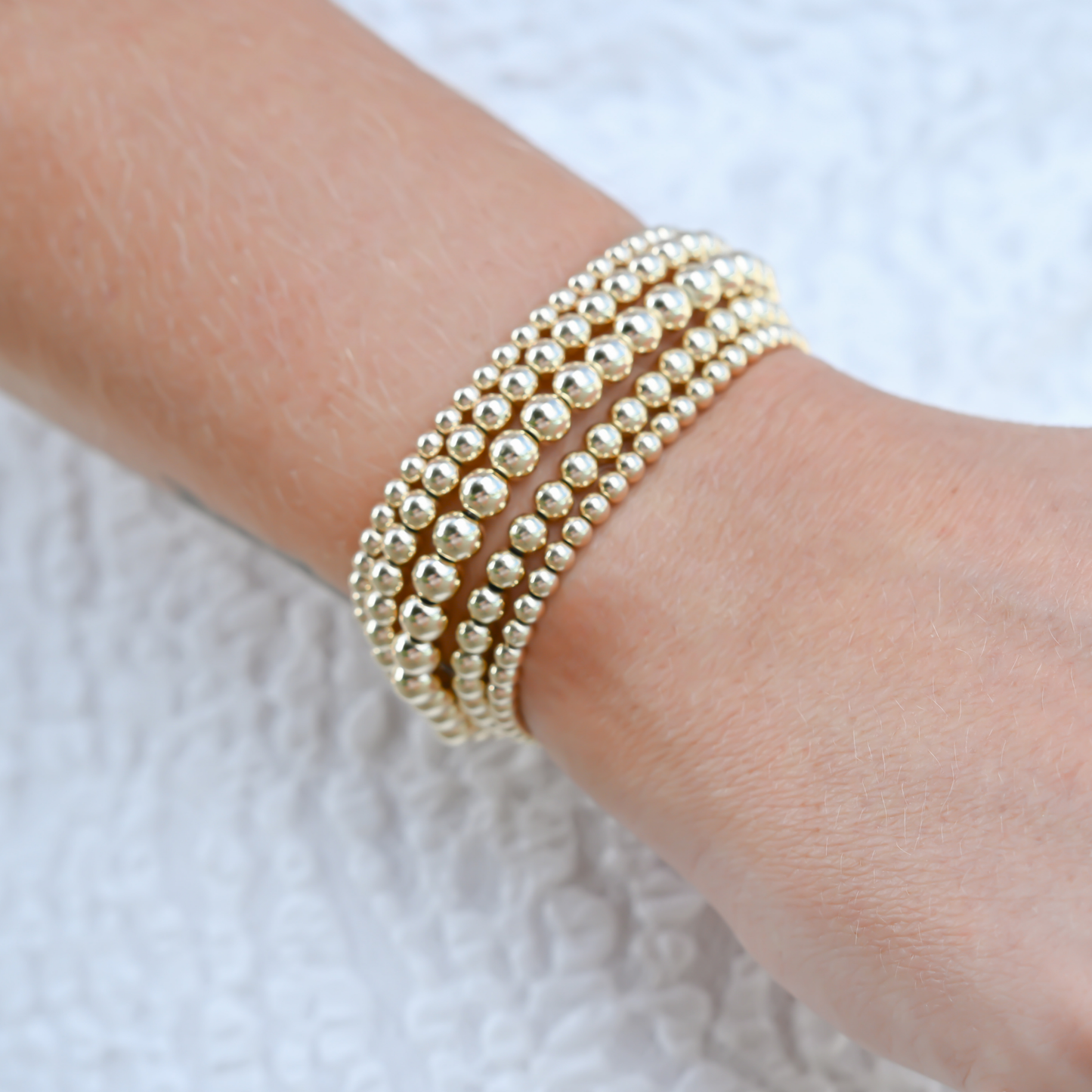 Gold filled LustraFlex™ bracelet by Gold Club by Shannon Hudson shown on a woman in a white dress.