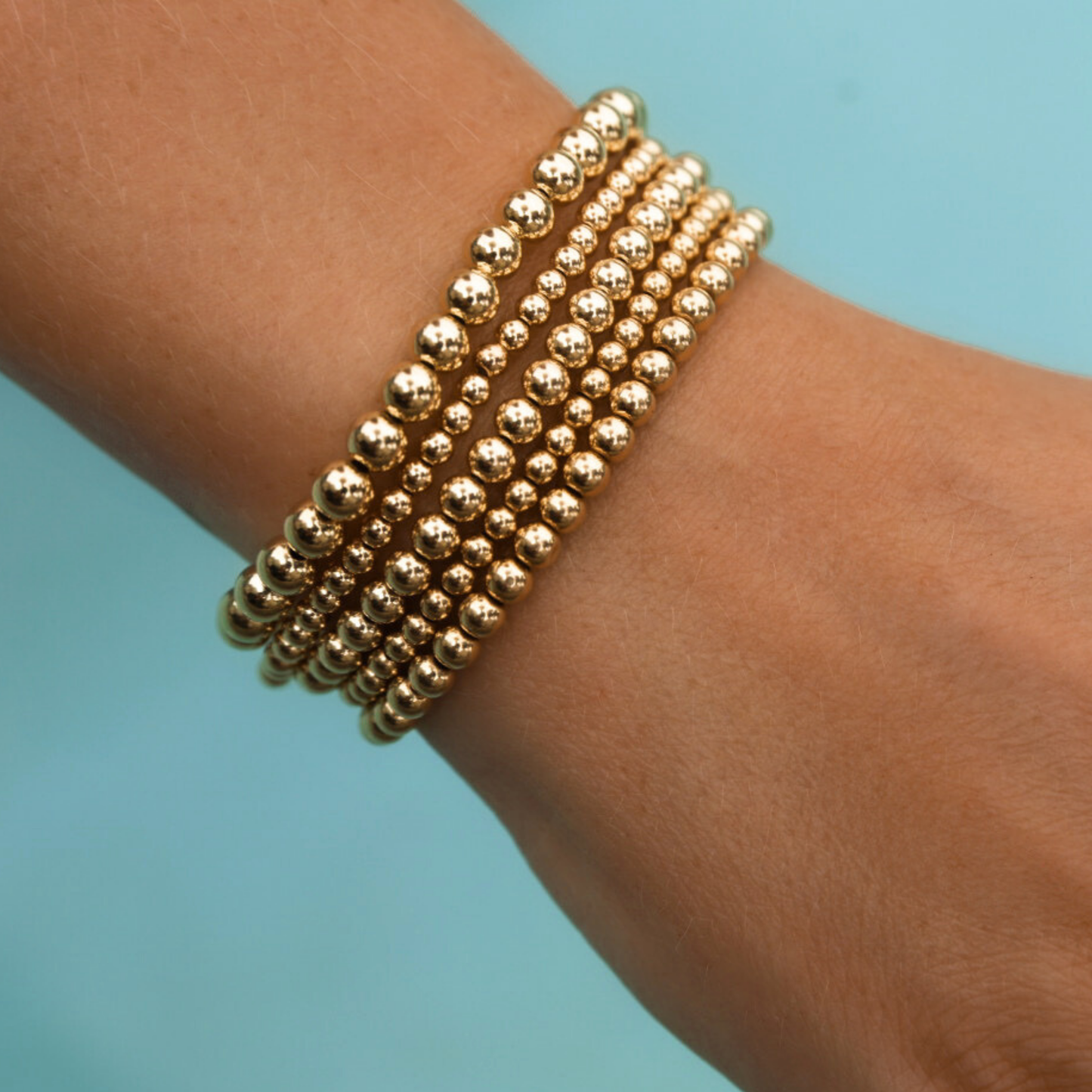 Gold-filled bracelet stack from Gold Club by Shannon Hudson displayed on a pool background—jewelry that is tarnish resistant, waterproof and sweat proof.