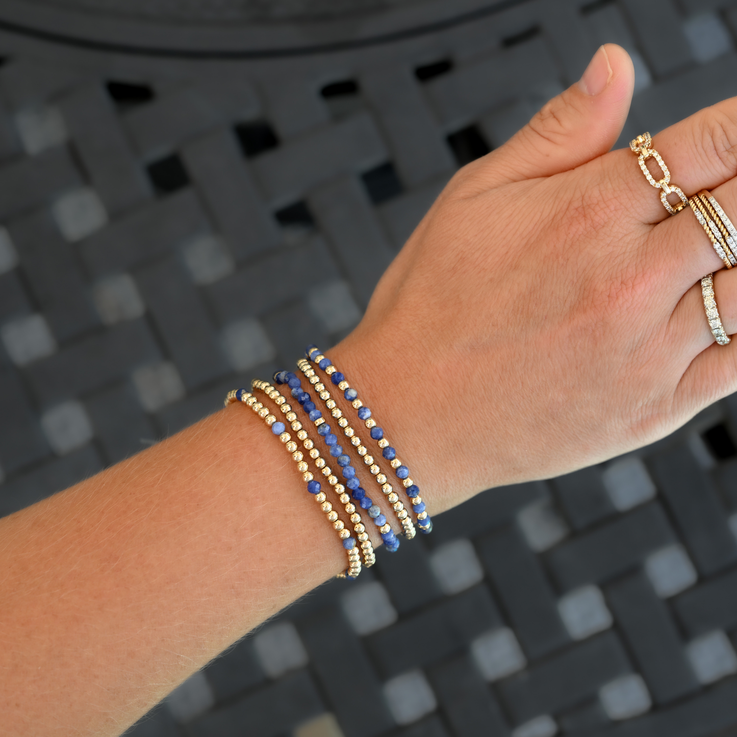 Five gold-filled and kyanite LustraFlex™ bracelets from Gold Club by Shannon Hudson, styled on an active woman’s wrist with rings.