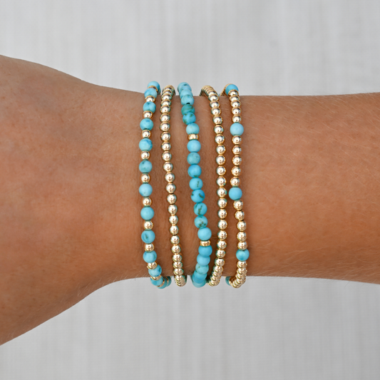 Turquoise bracelet stack styled on wrist with casual activewear, blending bold gemstone color with sleek gold in a luxe athletic look.