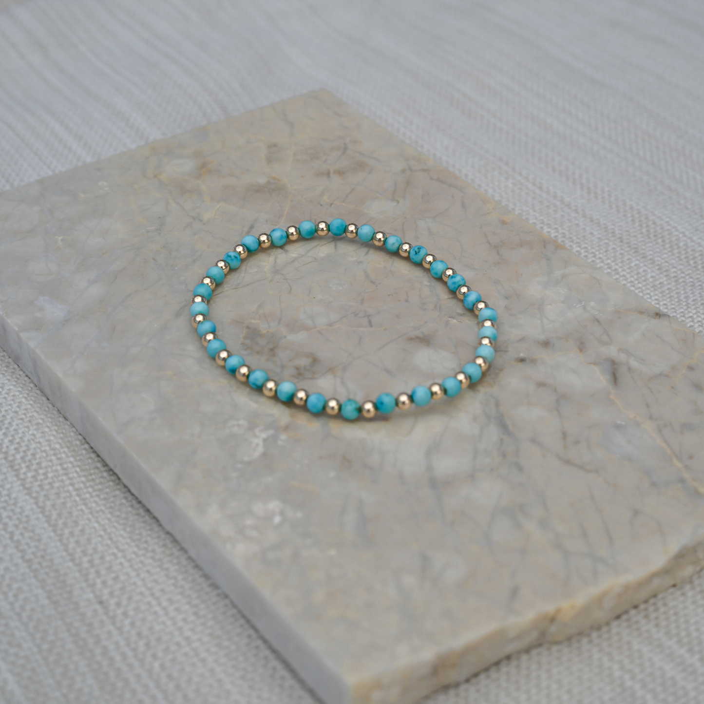 Close-up photo of the Turquoise Balanced bracelet placed on a stone tile, emphasizing color contrast and elevated materials.