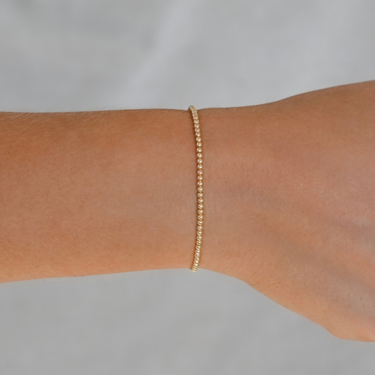 Gold bracelet on a person's wrist against a neutral background 2mm Gold LustraFlex™ Bracelet