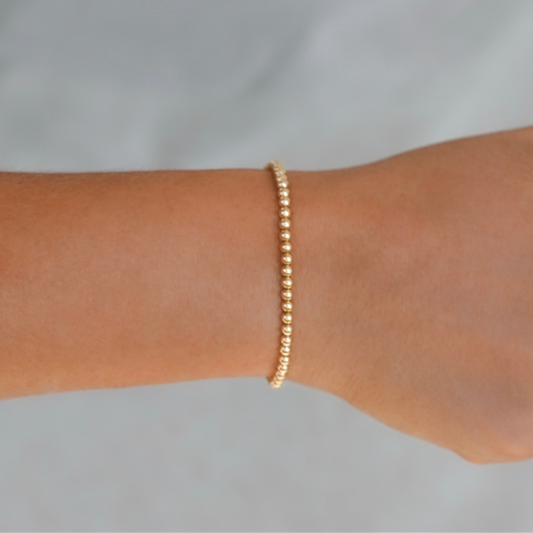 Gold bracelet on a person's wrist against a light gray background. 3mm Gold LustraFlex™ Bracelet