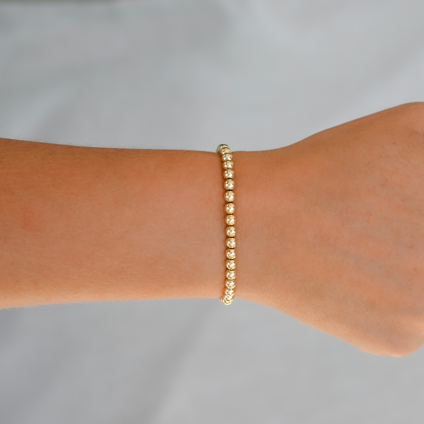 Gold LustraFlex™  bracelet on a wrist against a gray background. Gold Club by Shannon Hudson