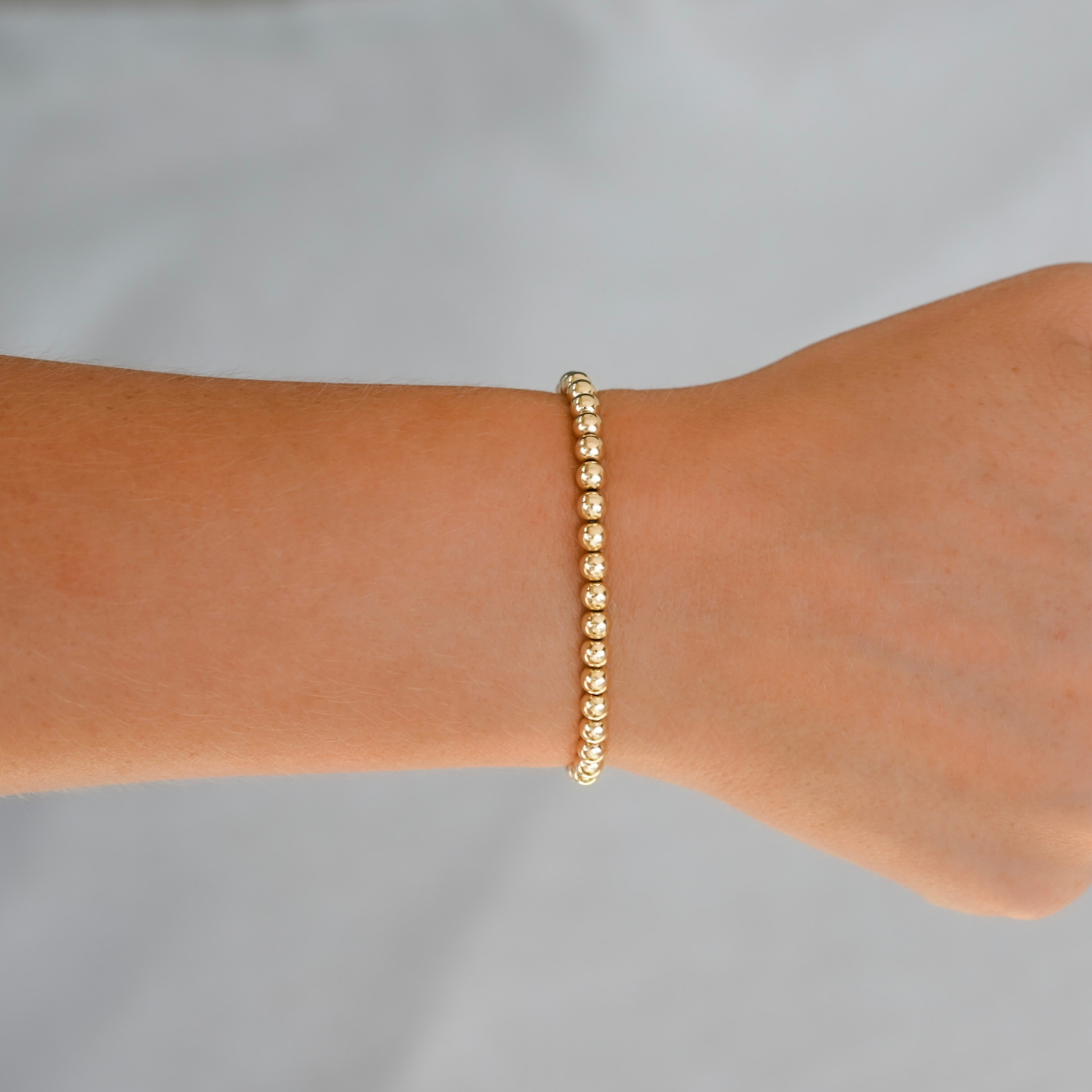 Gold LustraFlex™  bracelet on a wrist against a gray background. Gold Club by Shannon Hudson