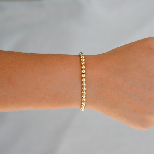 Gold LustraFlex™  bracelet on a wrist against a gray background. Gold Club by Shannon Hudson