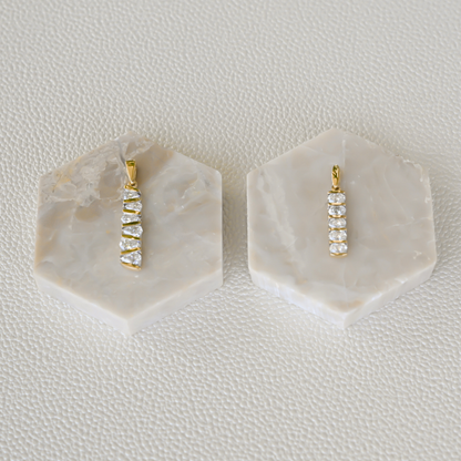 Two fine jewelry diamond bar pendants from Gold Club by Shannon Hudson on display in 14k gold