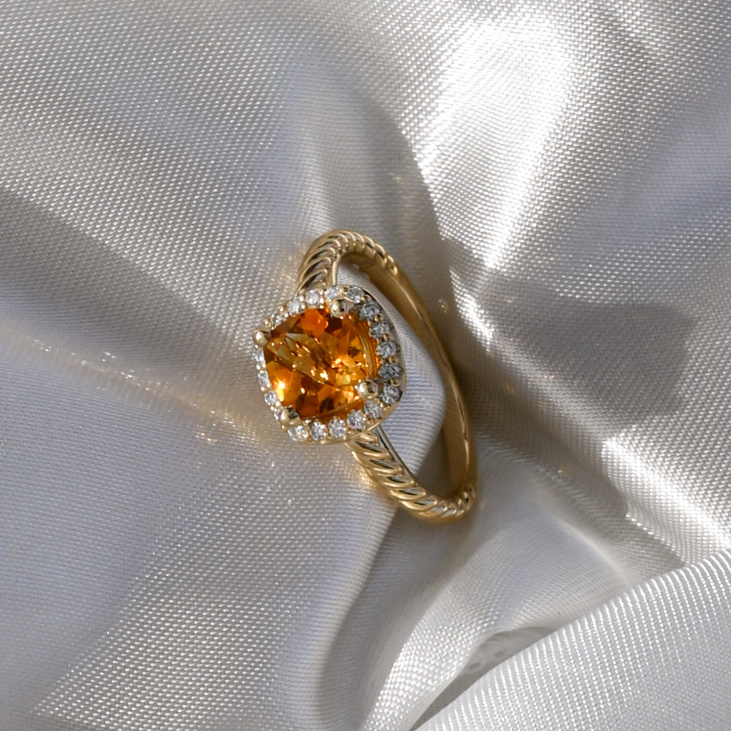 Gold club ring with a large citrine gemstone on a white fabric background