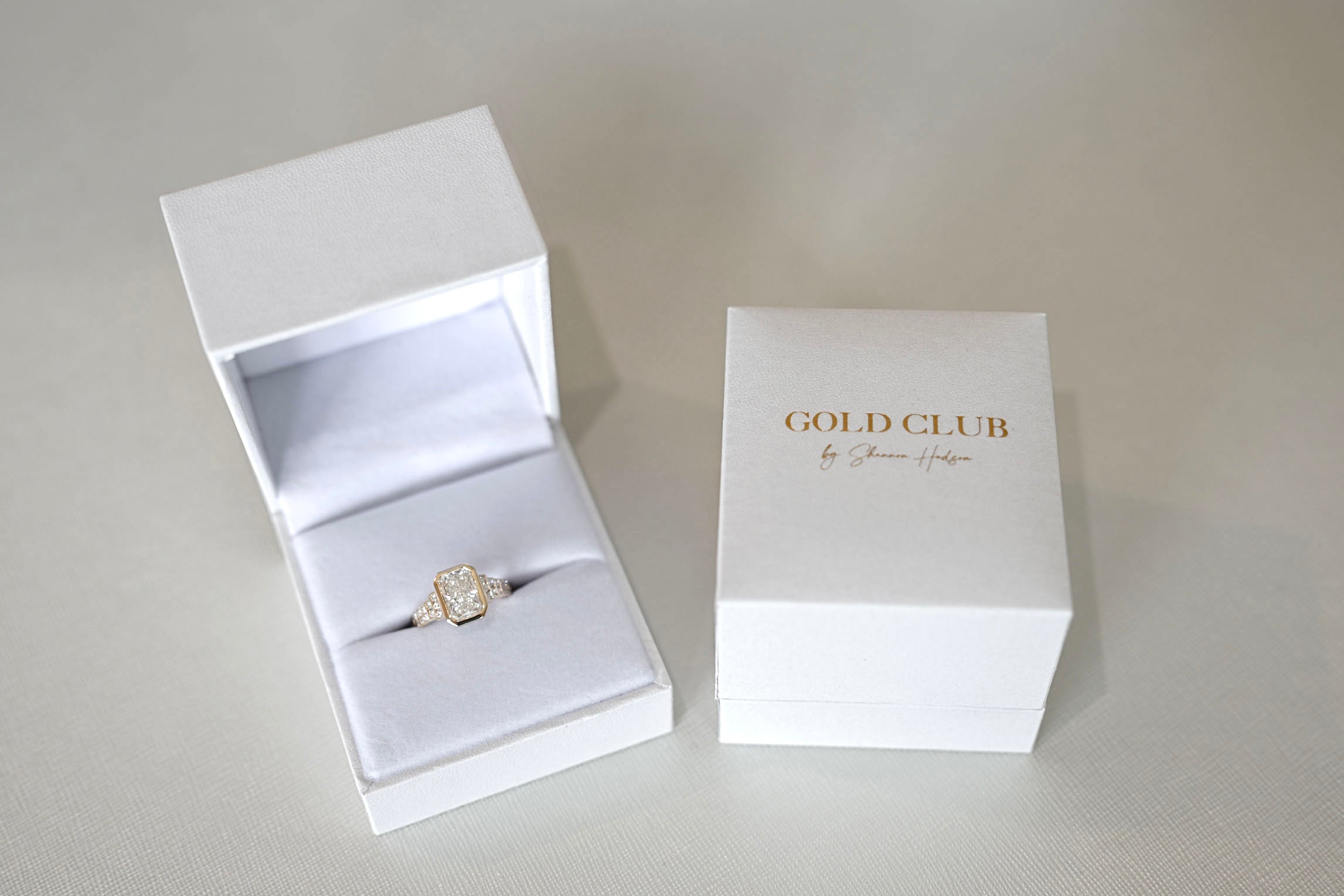 A Gold Club engagement ring and packaging.