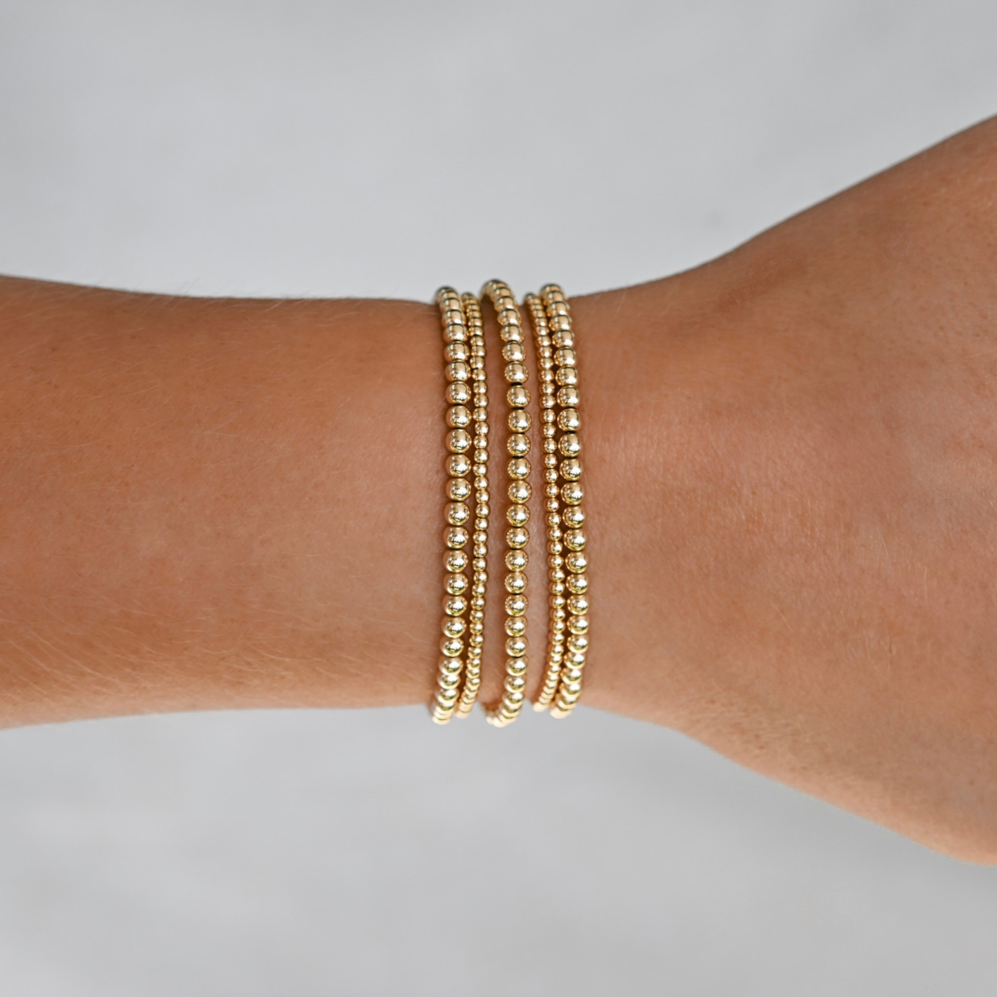 active lifestyle jewelry, gold filled bracelet stack on a wrist against a neutral background