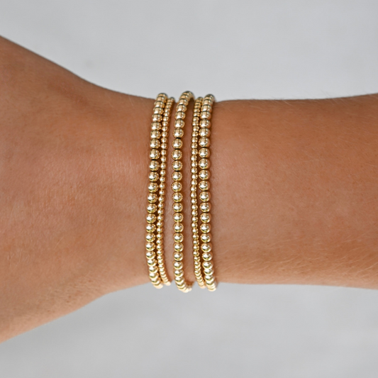 active lifestyle jewelry, gold filled bracelet stack on a wrist against a neutral background