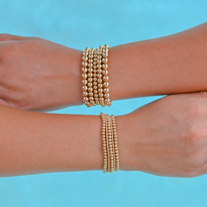 Gold-filled bracelets from Gold Club by Shannon Hudson displayed on a pool background—jewelry that is tarnish resistant, waterproof and sweat proof. 