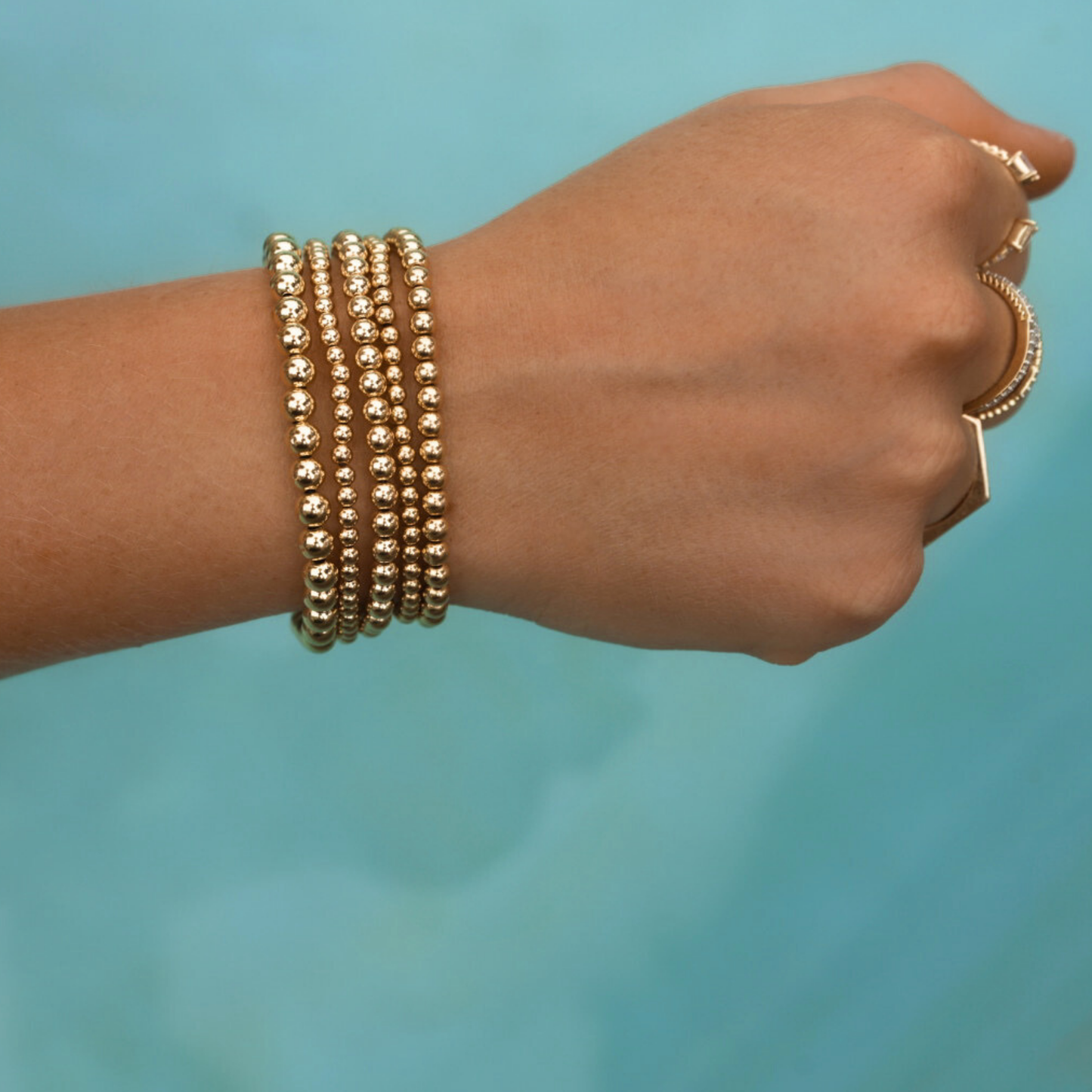 Gold-filled bracelet stack from Gold Club by Shannon Hudson displayed on a pool—jewelry designed for active lifestyles.