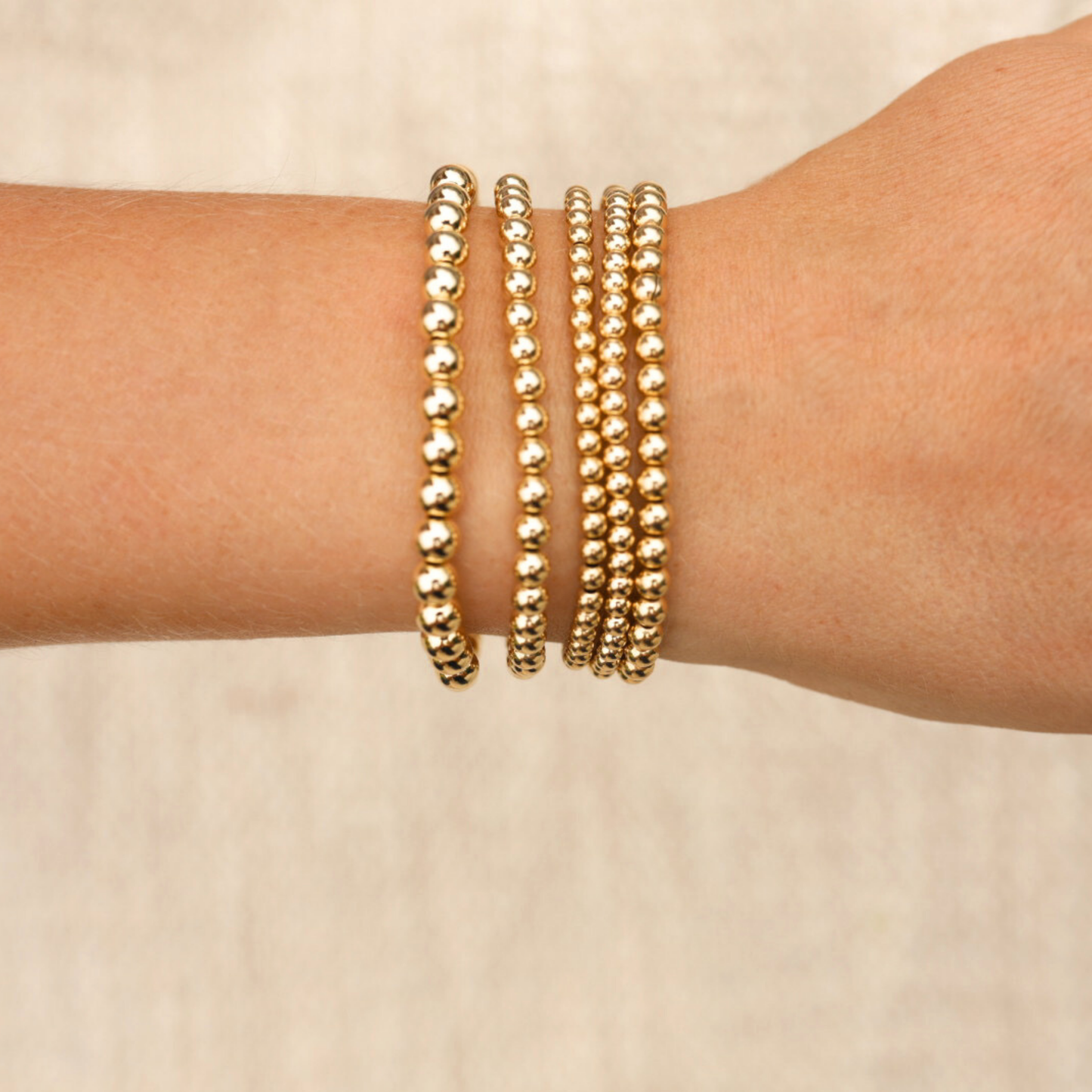 Gold-filled bracelets from Gold Club by Shannon Hudson displayed on a beige background—jewelry designed for active lifestyles.
