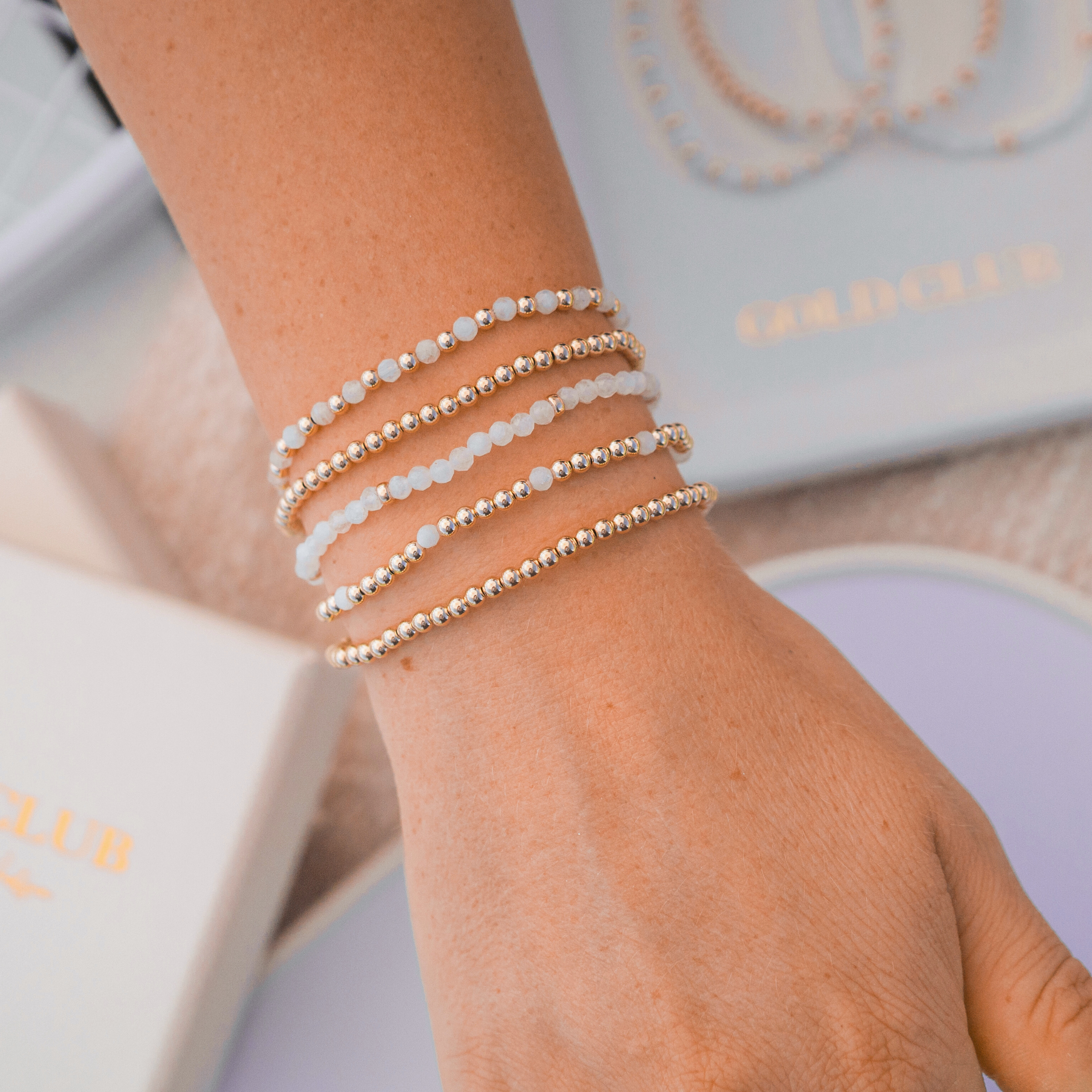 The Gold Club Every Line from Gold Club by Shannon Hudson picture a stack on a woman's wrist.