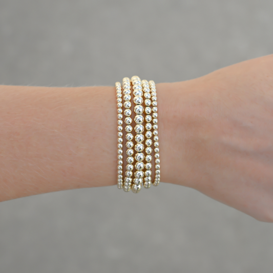 Close up of Gold Club’s signature LustraFlex™ elastic bracelet with different sizes gold filled beads.