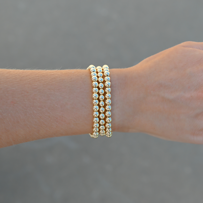 Gold-filled beaded bracelets featuring LustraFlex™ technology styled on a wrist with neutral background