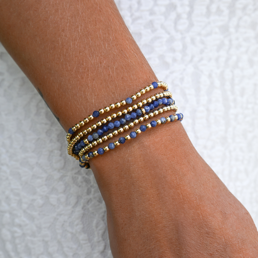 Active lifestyle jewelry – LustraFlex™ gold and gemstone bracelet styled on a woman's wrist with a white dress.