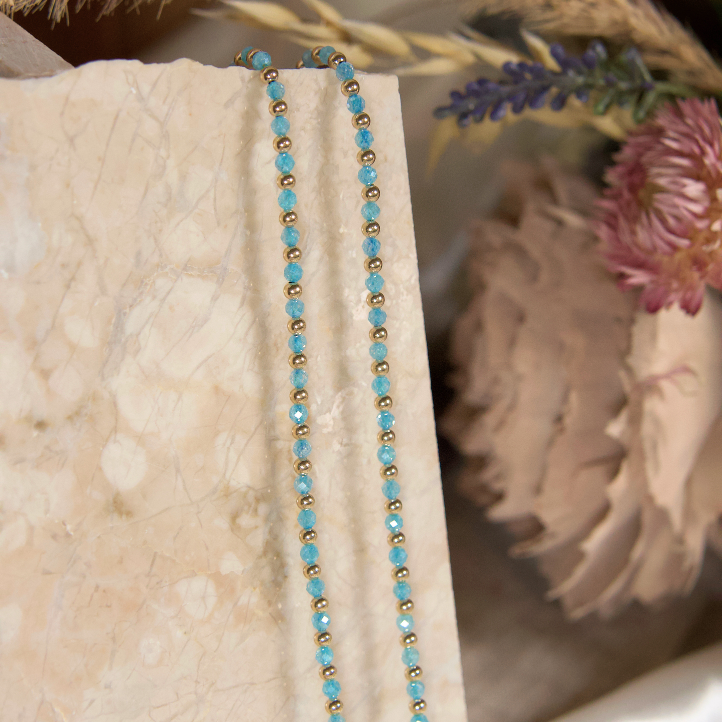 Light Blue (Aqua) and gold necklaces from Gold Club Jewelry House on a natural stone