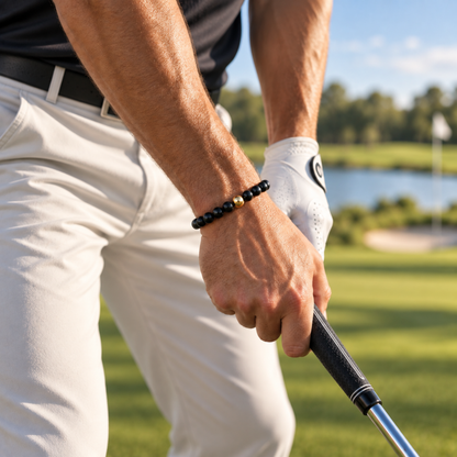 Men’s polished black natural stone bead bracelet with gold-filled bead on a golf course. jewelry you can play golf in 