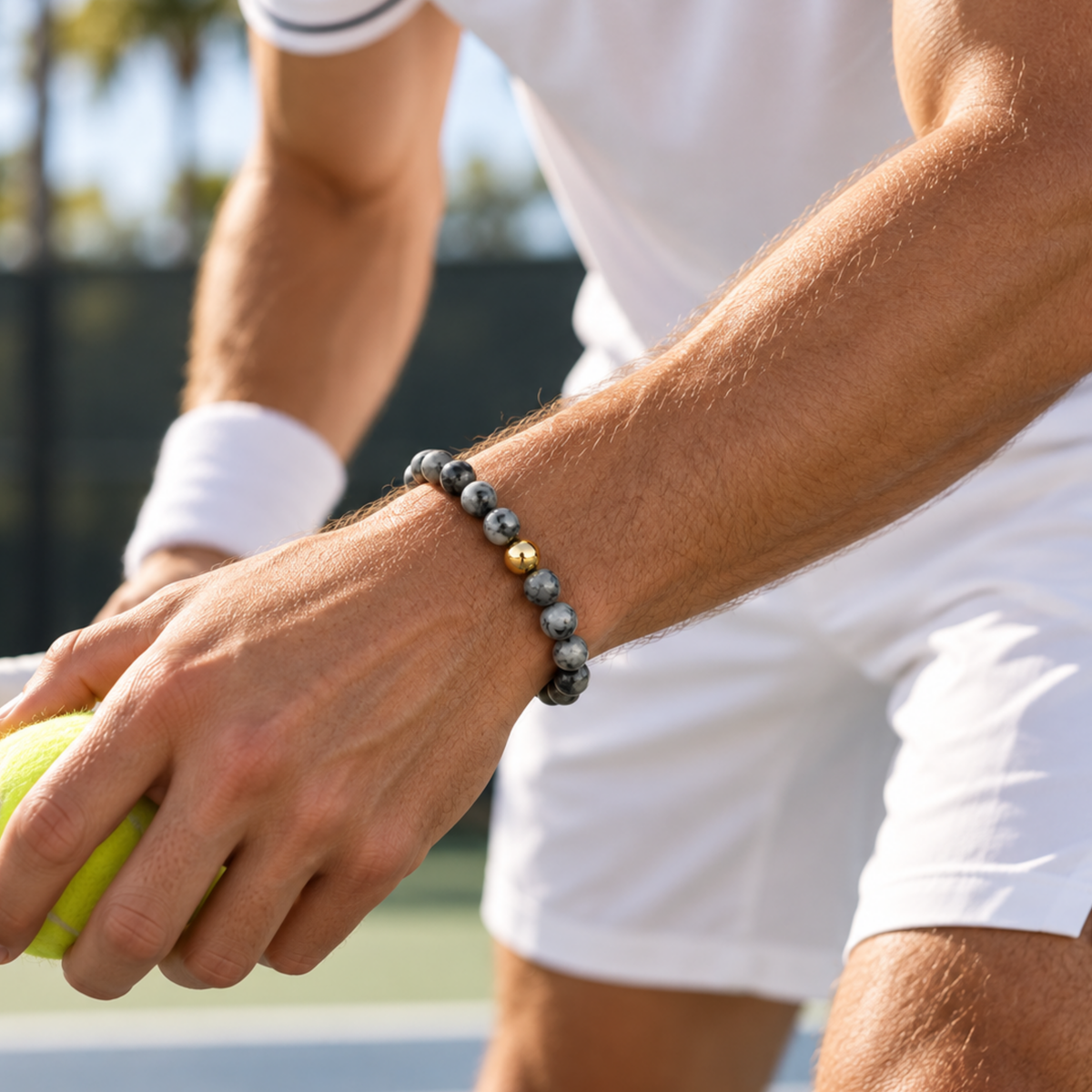 Men’s polished black natural stone bead bracelet with gold-filled bead on a tennis court. jewelry you can play tennis in 