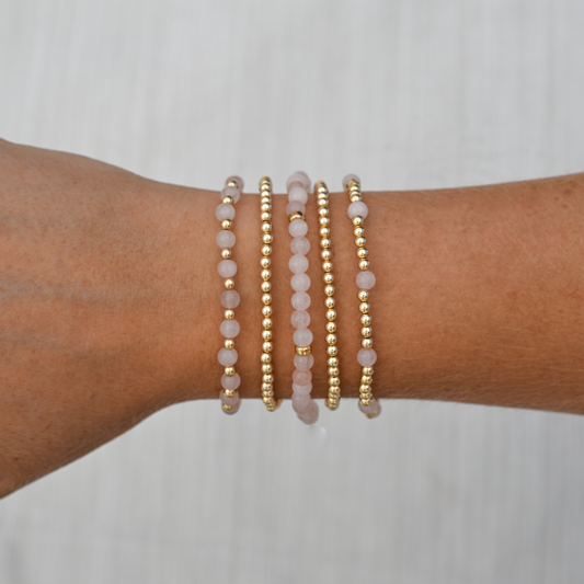 Pink Quartz Mini Stack styled on wrist in sunlight, featuring Arc, Muse, and Sun designs from the GOLD CLUB gemstone collection.