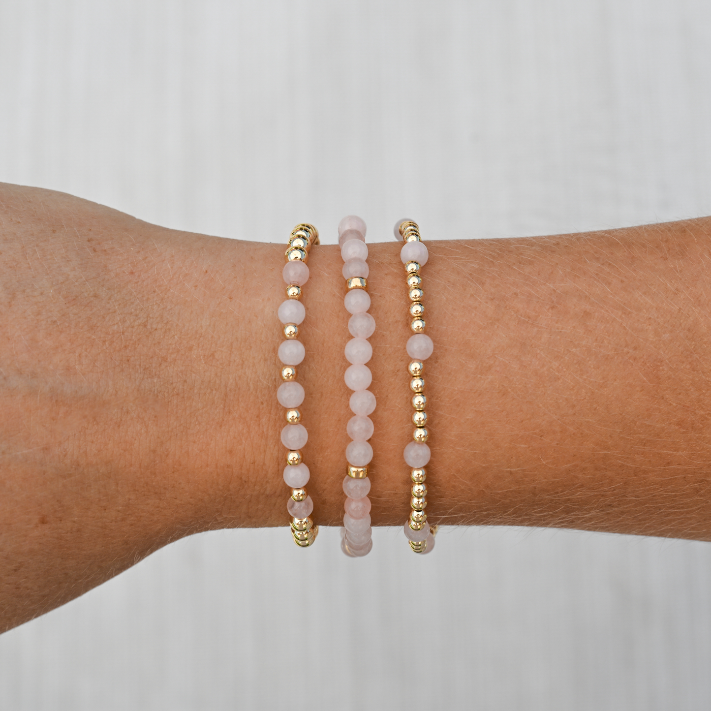 Detailed image of GOLD CLUB’s Pink Quartz Signature Stack showing layered gold-filled and pink gemstone bracelets for a soft, luxe finish.