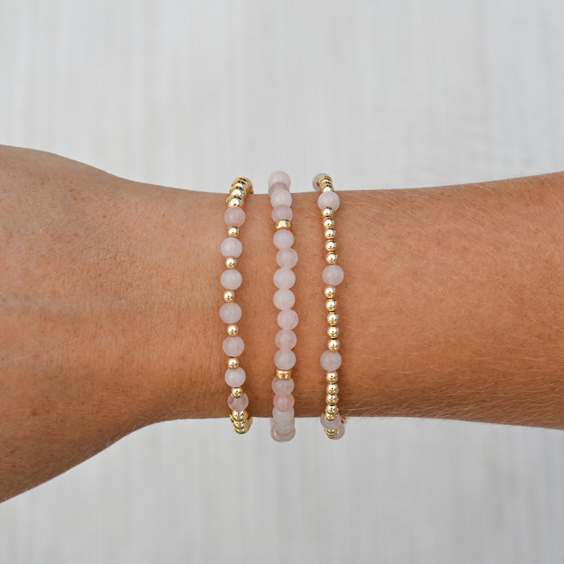 Detailed image of GOLD CLUB’s Pink Quartz Signature Stack showing layered gold-filled and pink gemstone bracelets for a soft, luxe finish.