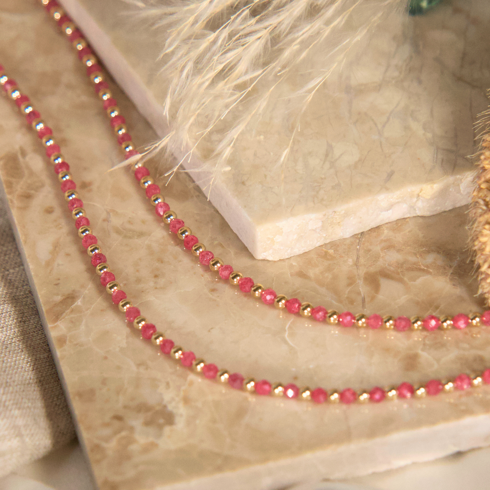 Pink Zircon and gold necklace close up on a natural stone 