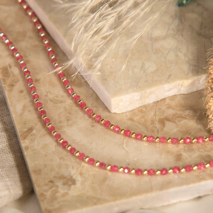 Pink Zircon and gold necklace close up on a natural stone 