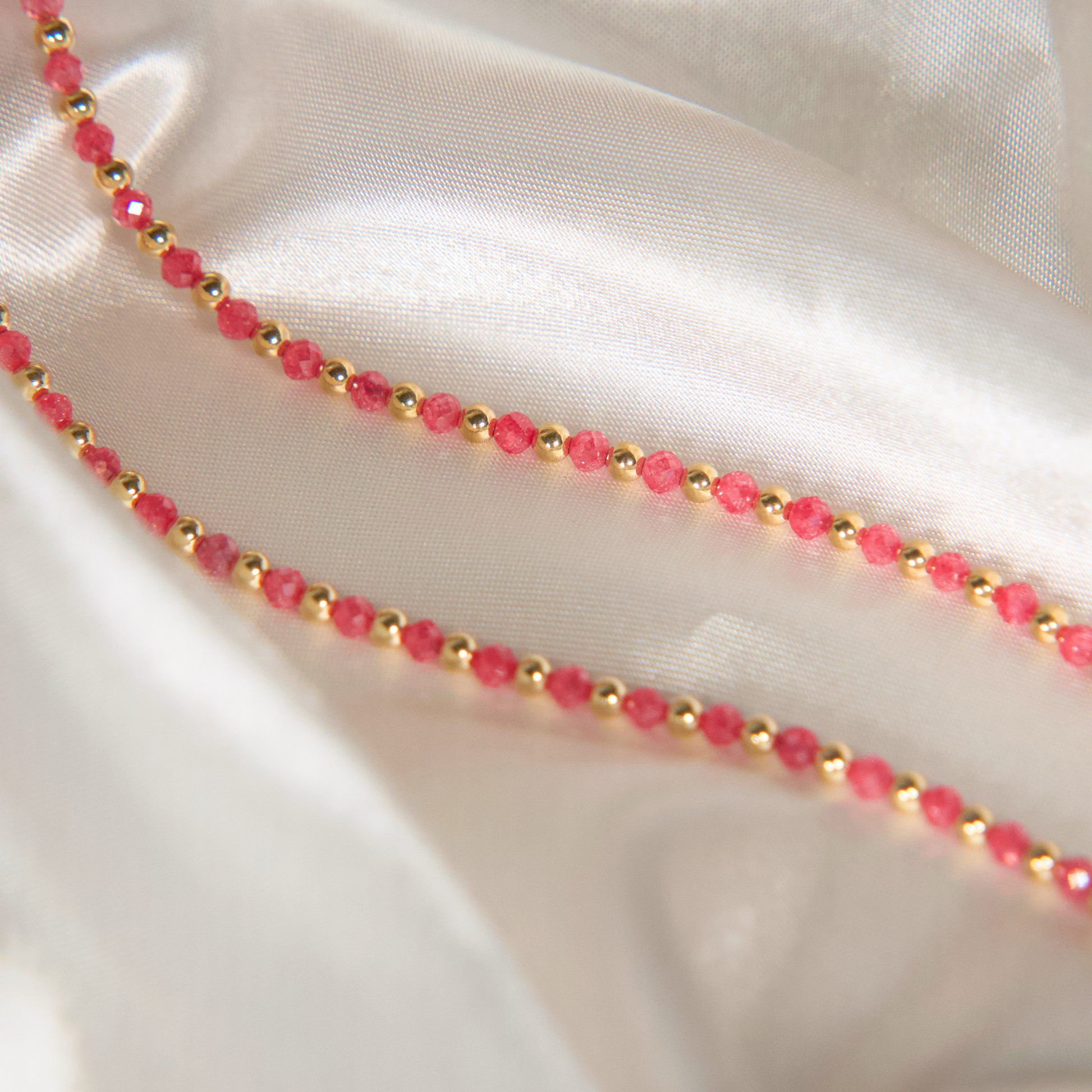 A pink zircon and gold necklace on satin 