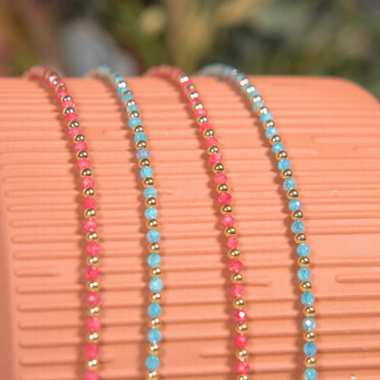 Pink Zircon and Light Blue (Aqua) Zircon necklaces laying over a vase