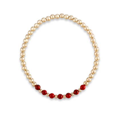 Overhead shot of the Red Agate Arc bracelet from GOLD CLUB by Shannon Hudson, featuring a centered red agate gemstone band on a curved gold-filled band.
