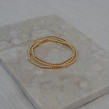 Set of three Gold Club by Shannon Hudson 2mm Gold LustraFlex™ Bracelet bracelets on a pretty tile